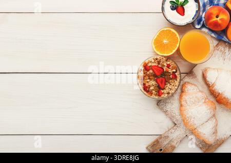 Frühstückskollektion mit Obst, Joghurt, Gebäck und Saft auf einem Holztisch Stockfoto
