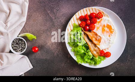 Gegrillte Tacos mit Ei, gebratenem Speck, Gemüse und Kräutern auf einem Teller mit Top-View-Webbanner Stockfoto