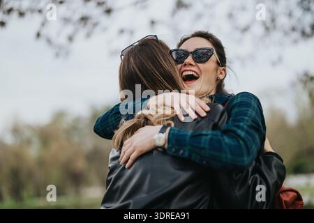 Zwei Frauen umarmen sich in einer fröhlichen Umarmung im Freien und halten Freundschaft und Glück fest Stockfoto