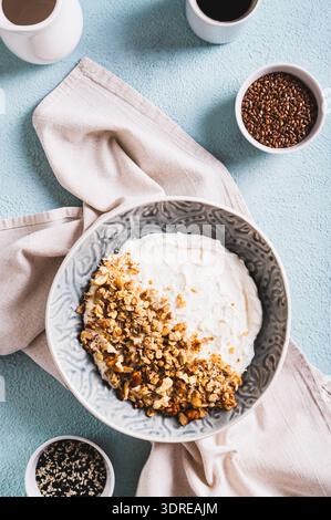 Müsli mit Nüssen in einer Schüssel mit klassischem Joghurt für gesunde Ernährung von oben und vertikal Stockfoto