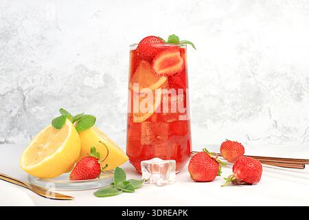 Erdbeere Iced Tea oder Minze Lemon Cocktail ist ein erfrischendes Sommergetränk. Gläser mit Beeren-Frucht-Limonade auf einem Lichtkrug Stockfoto