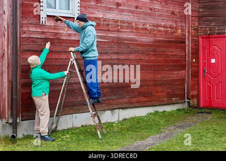 Ein Paar dekoriert das Bauernhaus für die Weihnachtsfeier. Stockfoto