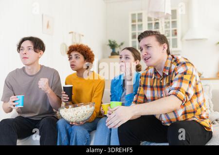 Eine Gruppe von Freunden, die sich zu Hause ein Fußballspiel im fernsehen anschauen. Fußballfans enttäuschten das Spiel mit dem fehlenden Tor. Freundschaftssport ente Stockfoto