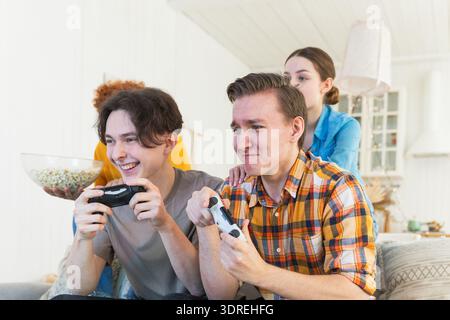 Heimparty. Fröhliche Gruppe von Freunden, die zu Hause Videospiele spielen. Fröhliche Gruppen-Freunde, die gemeinsam viel Spaß haben. Frien Stockfoto
