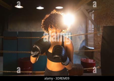 Aufschrei unabhängiger Mädels Macht. Wütende afroamerikanische Kämpferin mit Boxhandschuhen, die ziemlich aggressiv aussehen, auf bo zu stehen Stockfoto