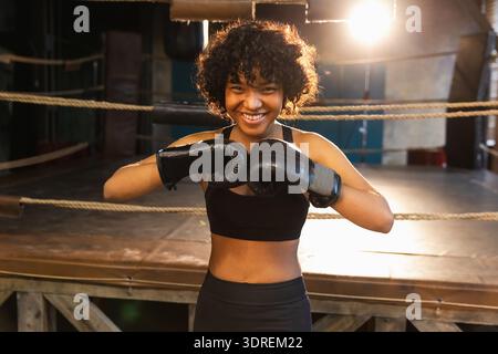 Aufschrei unabhängiger Mädels Macht. Wütende afroamerikanische Kämpferin mit Boxhandschuhen, die ziemlich aggressiv aussehen, auf bo zu stehen Stockfoto