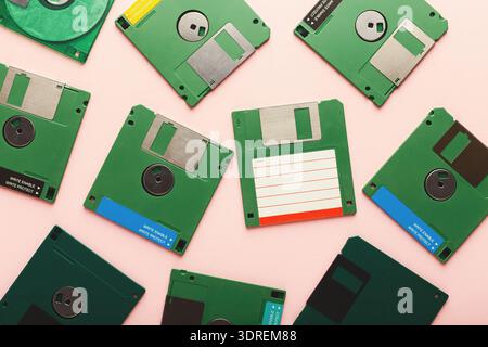 Sammlung grüner Disketten, die in einer Collage auf einer rosa Oberfläche angeordnet sind Stockfoto