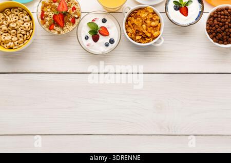 Auswahl an Frühstücksoptionen auf einem Holztisch mit verschiedenen Müsli und Früchten Stockfoto