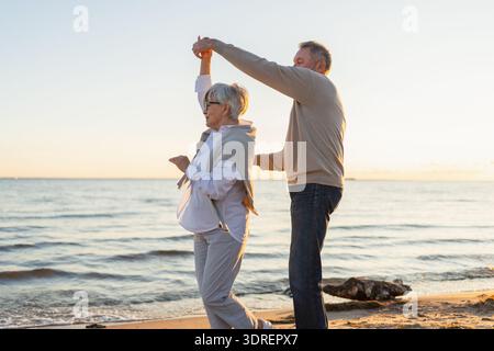 Bleiben Sie in Bewegung. Romantisches älteres Ehepaar, das gemeinsam am Strand im Freien tanzt. Glücklich lächelnde Familie pensionierte Mann Frau Stockfoto