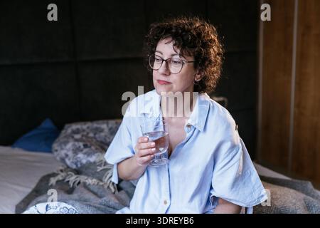 Weiße Frau in ihren 40ern, die eine Kapsel nahe dem Gesicht nimmt, Nahaufnahme Stockfoto