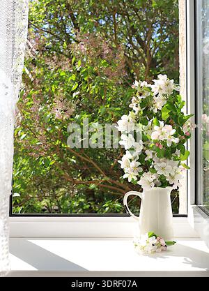 Blumenstrauß mit Frühlingsapfelblüten in einer Vase auf einem sonnigen Fenster, abstraktes Blumenarrangement, Stillleben mit blühender Baumkleie Stockfoto