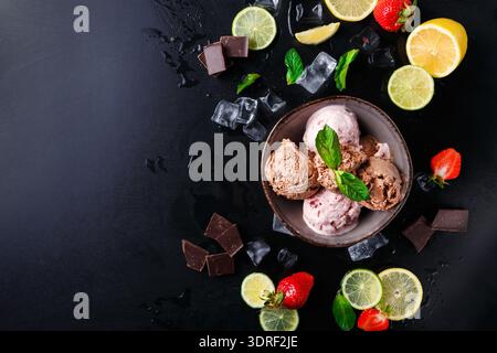 Drei Arten von Eis mit Früchten und Schokolade auf einer schwarzen Oberfläche Stockfoto