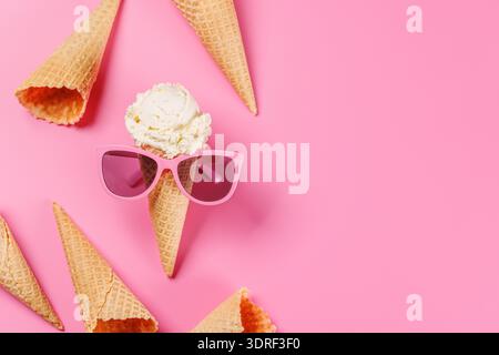 Ein verspielter Eisbecher mit stylischer Sonnenbrille vor einem leuchtend rosa Hintergrund Stockfoto