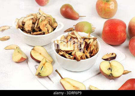 Hausgemachte Apfelchips in einer Tasse mit Äpfeln auf weißem Hintergrund, im Herbst werden Äpfel im Ofen oder Trockner gebacken und gelagert Stockfoto