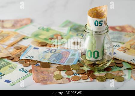 Geld im Glas und Euro-Banknoten auf Marmortisch. Geld sparendes Konzept Stockfoto