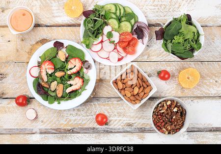 Gemüsesalat mit Garnelen, Gurke, Kirschtomaten, Radieschen, Honig, Nüsse und frische Rucola, gesundes natürliches Frühstück mit Stockfoto