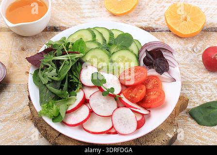Grüner Gemüsesalat mit Kirschtomaten, Gurke, Rettich und frischer Rucola, Entgiftungsdiät. Gesundes natürliches Frühstück für das Gewicht Stockfoto