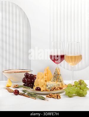 Stillleben mit Gourmet-Blaukäse, Parmesan, Trauben, Honig, Nüssen, rosmarin und Wein. Weinprobe. Käseplatte mit saisonaler Auswahl Stockfoto