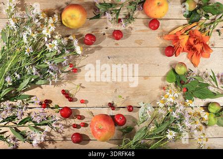 Sommer Kirschbeeren und Früchte auf einem hölzernen Hintergrund mit Lilien und Gänseblümchen, wilde Blumen, Dorfernte, gesunde natürliche f Stockfoto