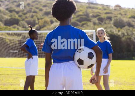 Fußball spielen, verschiedene Mädchen in blauen Hemden, die auf dem Schulfeld Ball halten Stockfoto