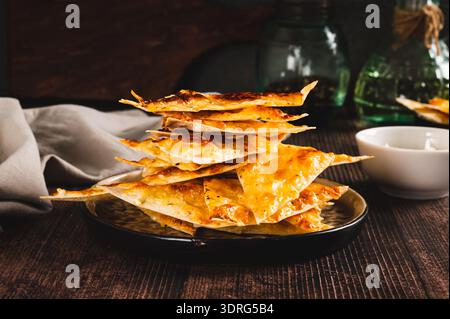 Hausgemachte Pita Chips mit Käse und Knoblauch auf einem Brett auf dem Tisch Stockfoto