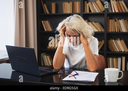 Kopfschmerzen. Frau mittleren Alters, die Schläfe berührt und Stress erlebt. Reife alte Dame müde der Arbeit, Kopfschmerzen, krankes Rubbi Stockfoto