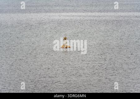 Gelbe Boje schwimmt auf ruhiger Wasseroberfläche mit sanften Kräuselungen, maritimer Schifffahrtsmarker auf offenem Meer Stockfoto