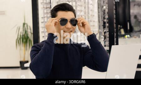 Junger Mann mit Sonnenbrille im Optikgeschäft Stockfoto