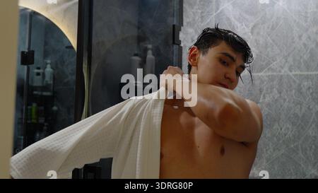 Ein Mann, der ein weißes Hemd im Badezimmer anzieht Stockfoto