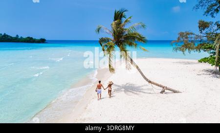 Ein Paar genießt einen romantischen Spaziergang entlang eines unberührten Strandes unter einem klaren blauen Himmel Stockfoto