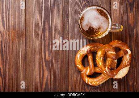 Bierkrug und Brezel auf Holztisch Stockfoto