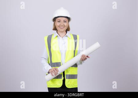 Lächelnde Architektin im Helm mit Papierrolle Stockfoto