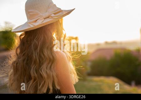 Frau mit Hut, die den Sonnenuntergang im Urlaub beobachtet Stockfoto