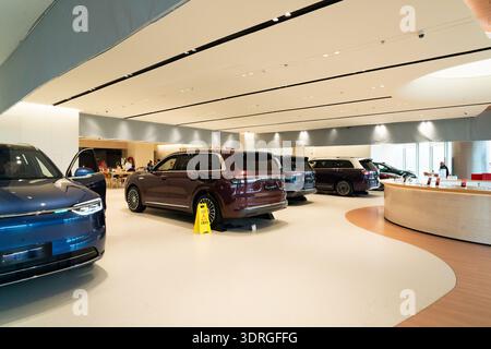 Moderne elektrische SUVs im eleganten Showroom mit geschwungener Decke und minimalistischem Design Stockfoto