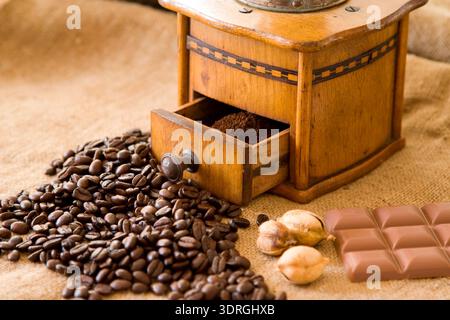 Alte Kaffeemühle mit Kaffeebohnen und Schokolade Stockfoto