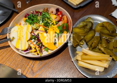 Vietnamesischer Salat mit Garnelen und Mango, serviert mit eingelegtem Gemüse auf Holztisch Stockfoto