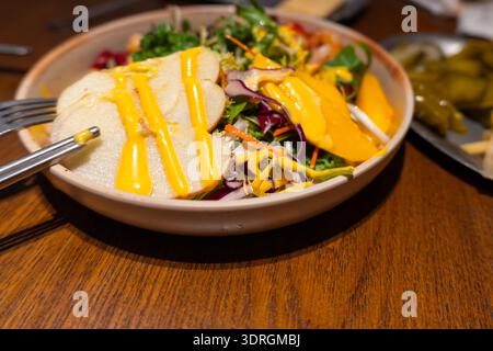 Italienischer Salat mit gegrilltem Huhn, frischem Gemüse und Käsesoße auf Holztisch Stockfoto