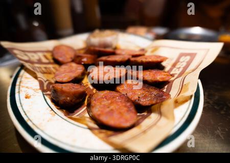 Portugiesische Chourico-Würstchen auf einem mit Papier gefütterten Teller im Restaurant Stockfoto