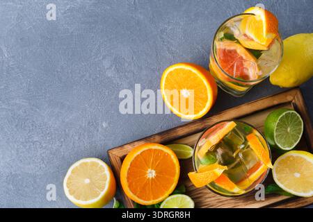 Erfrischende Getränke mit Zitrusfrüchten auf einem Holztablett in hellem Ambiente Stockfoto