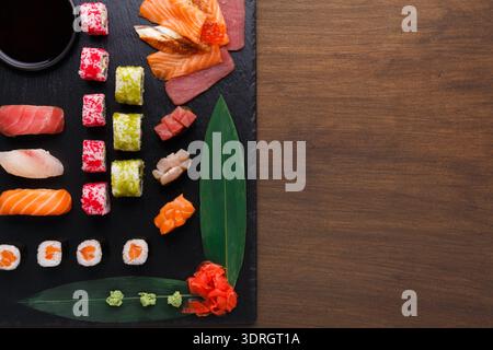 Sammlung von Sushi-Sorten auf einem dunklen Servierbrett im Mosaikstil Stockfoto
