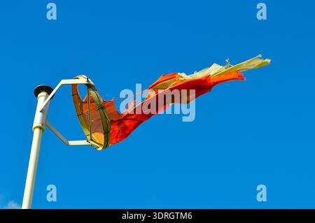 Rot-weiße Windsocke, die von starkem Wind in der Küstenregion unter klarem blauem Himmel gerissen wurde Stockfoto