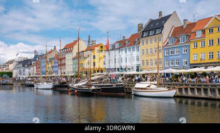 Erkunden Sie die pulsierende Uferpromenade von Nyhavn in Kopenhagen mit farbenfrohen Gebäuden und Booten Stockfoto