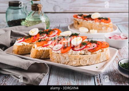 Appetitliche Bruschetta mit Ricotta, Tomate, Rettich und Wachtelei auf einem Teller Stockfoto