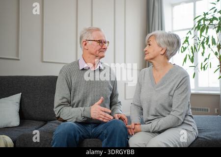 Älteres erwachsenes Ehepaar, das zu Hause spricht. Der alte Mann und die Frau sprechen im mittleren Alter lächelnd lachend und genießen die gemeinsame Zeit. Grand Stockfoto