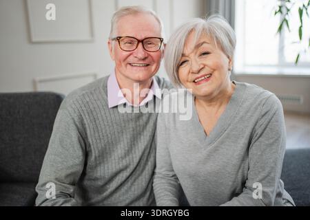 Älteres erwachsenes Ehepaar umarmt zu Hause. Alter Mann und Frau im mittleren Alter, die sich mit Zärtlichkeit umarmen, lieben es, süße Bindungen zu genießen Stockfoto
