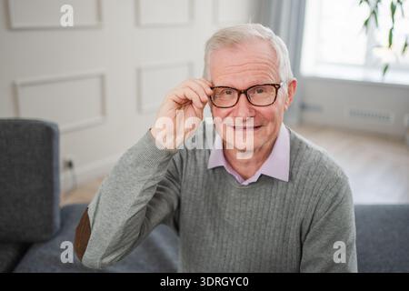 Porträt eines selbstbewussten, stilvollen europäischen Seniorenmannes mittleren Alters zu Hause. Älterer reifer Mann der 70er Jahre lächelt. Glückliche attraktive Seniorengra Stockfoto