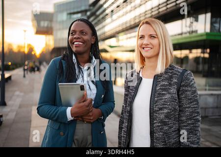 Geschäftsfrauen, die im Freien spazieren und sich bei Sonnenuntergang unterhalten Stockfoto
