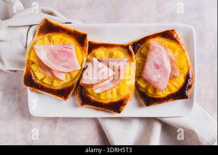Nahaufnahme von knusprigen Torten mit Ananas und Schinken auf einem Teller auf der Tischansicht Stockfoto