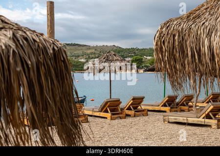 Strohschirme am leeren Strand nach der Touristensaison im Ferienort Ksamil, Albanien Stockfoto