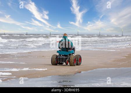 Mann mit Handicap am Strand mit Strandrollstuhl Stockfoto